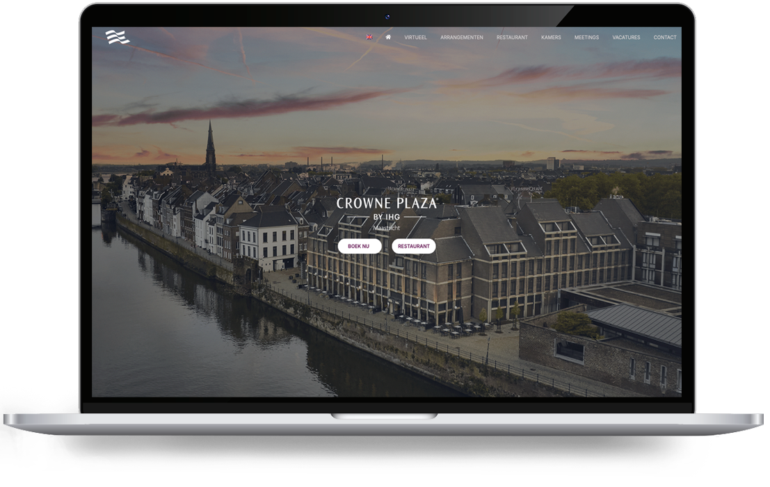 Crowne Plaza von Webdesign Holland - LeTigre Webdesign Holland Laptop-Bildschirm mit dem Hauptbild des Crowne Plaza Maastricht: eine Stadt am Flussufer bei Sonnenuntergang, mit Navigationsleiste und den beiden Handlungsaufforderungen „Jetzt buchen“ und „Restaurant“